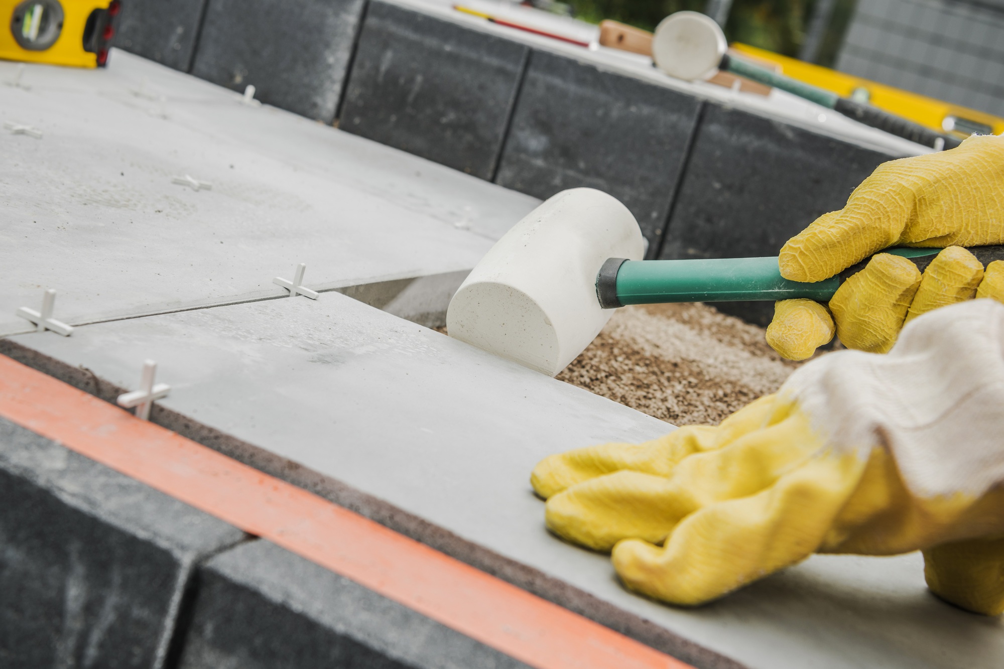 Construction Worker Leveling Stone Pavers in a Landscaping Project During Daylight Hours